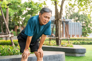 Senior asian man tired during jogging at outdoor nature park. Mature asian male intense training workout challenge breathing exhausted. Healthy and activity lifestyle concept.