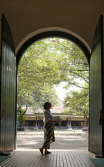 A silhouette of a woman standing under archway of an old Javanese vintage architectural building © Simon