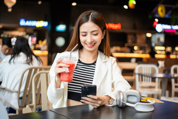 Young asian smiling woman with soft drink sitting in the coffee shop cafe. Business woman laughing talking with friend inside restaurant. People lifestyle concept.