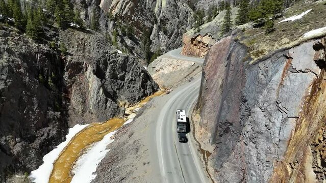 Top Down View of an RV Towing a Jeep, Driving through a winding gorge, next to a gold colored river, Million Dollar Highway, Uncompahgre river, Ouray Colorado