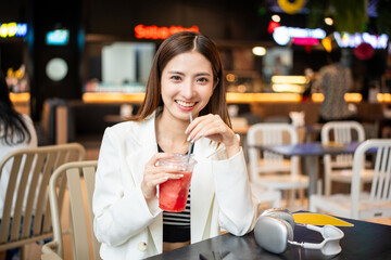 Young asian smiling woman with soft drink sitting in the coffee shop cafe. Business woman laughing talking with friend inside restaurant. People lifestyle concept.