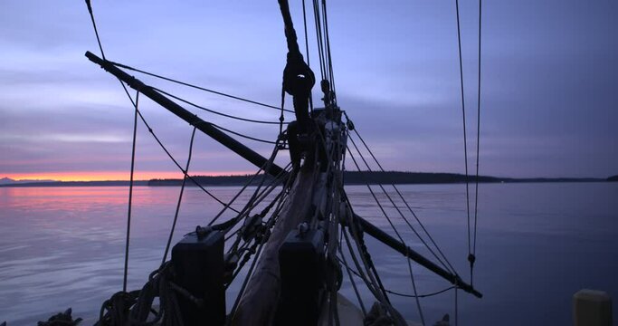 1700s sailing ship underway at sea in the Strait of Juan de Fuca. Sunrise on a cloudy day. Medium shot of the bowsprit and lines. Slight roll with the ship.