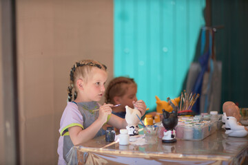 Girls 4-5 years old are sitting at a table and painting with colorful paints. Children's creativity. Children's hobbies.