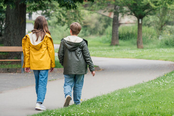 Fototapeta premium A teenage girl and boy are walking in a spring park. Wearing lightweight weather jackets