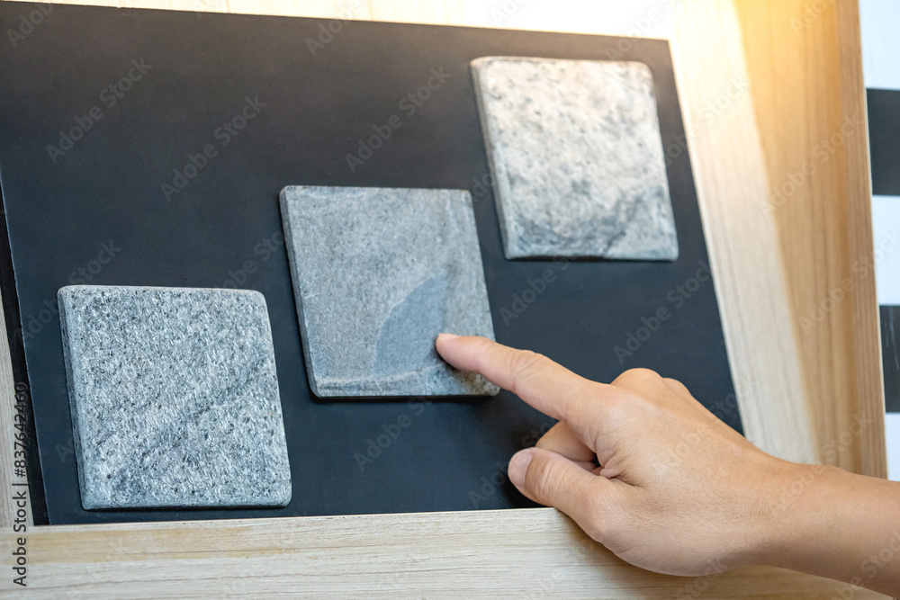 Wall mural architect hand choosing and pointing at stone tile material samples on the collection display in the