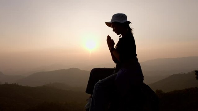 Silhouette of a woman  prayer on mountain at sunrise. concept of religion. Christians pray to jesus christ for calmness. In morning people got to a quiet place and prayed.