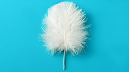 Fototapeta premium A tight shot of a white feather balanced on a stick against a blue backdrop A solitary teardrop hangs from the feather's tip, traversing its length