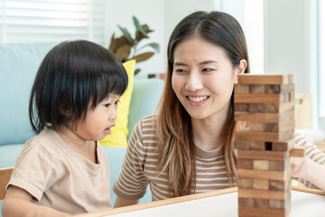 Asia Happy single mother playing learning games janga with the little girl. Funny family is happy...