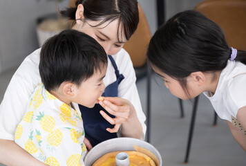 一緒にお菓子を作る母親と家族　味見する子供