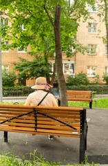 old lonely woman with hat sitting on bench with park  © Anna Ismagilova