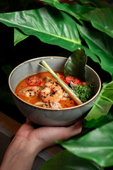 A popular dish of Asian cuisine is Tom Yam soup, cooked with shrimp, lemongrass, galangal and lime. Thai soup with a sour and spicy taste in Minsk around palm leaves