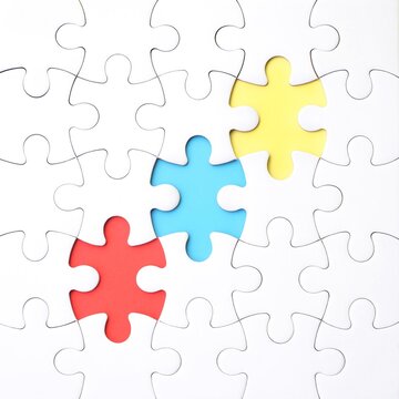 An incomplete white jigsaw puzzle with three missing pieces, each in a different primary color: blue, red, and yellow