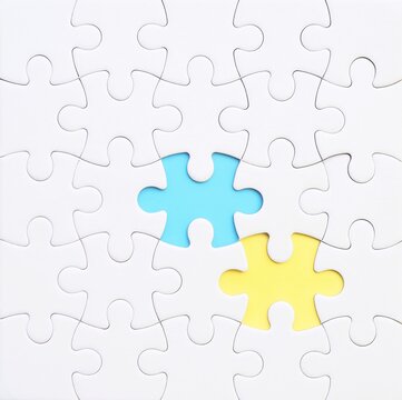 An incomplete white jigsaw puzzle with two missing pieces, each in a different color: blue and yellow