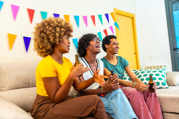 Obraz premium Multi-ethnic friends sitting on the sofa drinking beer during party
