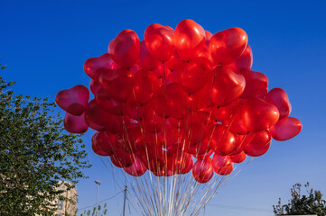bunch of many red balloons in the shape of a heart on the background of blue sky