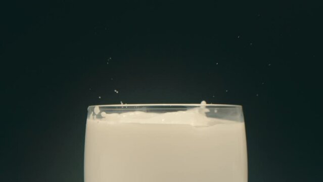 Oreo cookie falling into glass of milk and splashing in slow motion