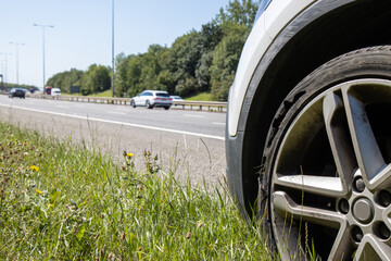 A car with a flat tyre after a large blow out on the highway showing a large slit in the tyre at the side of the M25 motorway in London in the UK