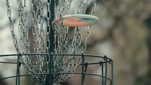 Disc golf frisbee hits chains and falls into basket in slow motion