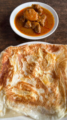 Top view picture of "roti canai telur" with lamb curry on table during breakfast. A flatbread mix with egg.