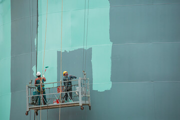 The male worker takes the cable car holding an industrial painting brush used for shell plate tank oil surface surface green