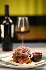 Shish kebab with onions and ketchup served in a restaurant for dinner, meat and wine. The concept of a chic dinner