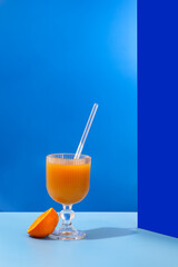 A glass of refreshing orange juice with a blue tint is placed on a table