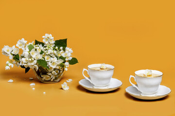 Jasmine tea with fresh flowers isolated on orange background