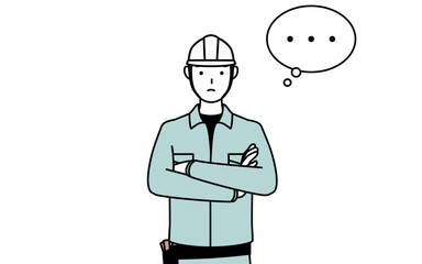 腕を組んで考えるヘルメットと作業着姿の男性