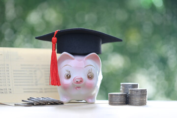 Graduation hat on piggy and stack of coins money on natural green background, Saving money for education concept