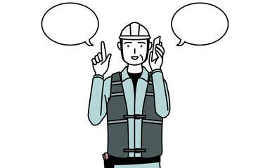 電話をしながら指さしをするヘルメットと作業着姿のシニア男性技師