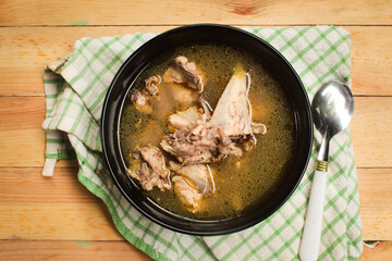 a bowl of chicken soup on a wooden table