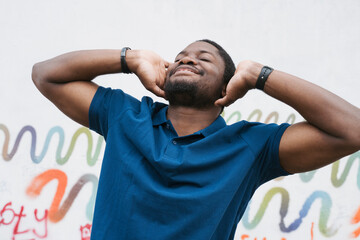 Happy man covering ears and standing in front of graffiti wall