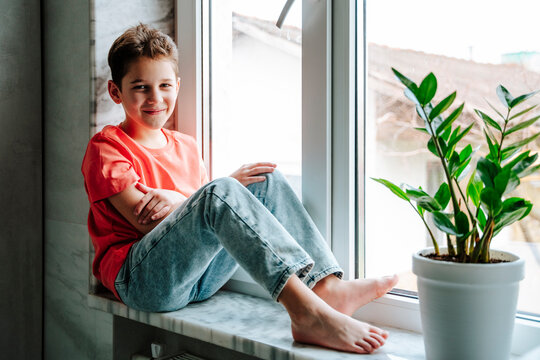 Smiling boy sitting on window sill