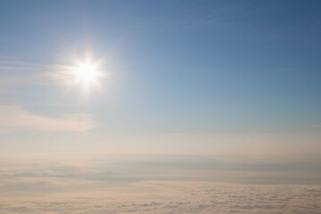 View of sunrise over white puffy clouds on horizon.