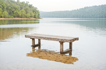 Naklejka premium Wooden bench on lake with reflection