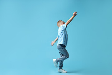 Fototapeta premium Happy little boy dancing on light blue background. Space for text