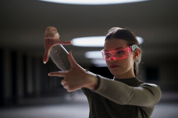 Woman wearing smart glasses looking through finger frame in underground parking