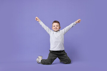 Happy little boy dancing on violet background