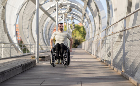 Man with disability moving through wheelchair on bridge