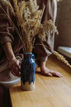 Potter decorating vase with pampas grass at desk in workshop