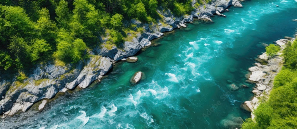 Poster aerial drone captures a strong, clear mountain river winding through a stone-lined coast and lush fo