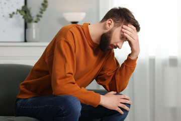 Overwhelmed man sitting on sofa at home