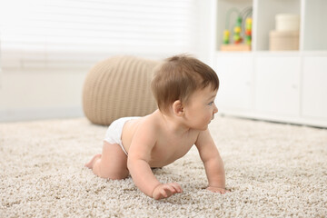 Cute baby boy crawling on carpet at home