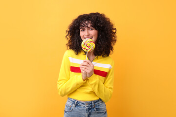 Beautiful woman with lollipop on yellow background