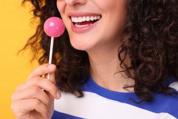Woman with lollipop on yellow background, closeup