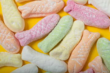 Marshmallows in the shape of little fish on a yellow background