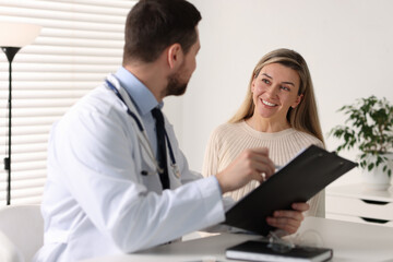 Fototapeta premium Professional doctor working with patient at white table in hospital