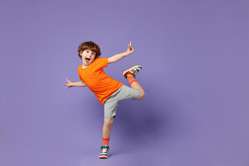 Happy little boy dancing on violet background