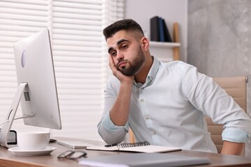 Overwhelmed man sitting at table in office