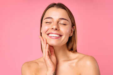 Portrait of a young woman with radiant skin and natural beauty on a pink background